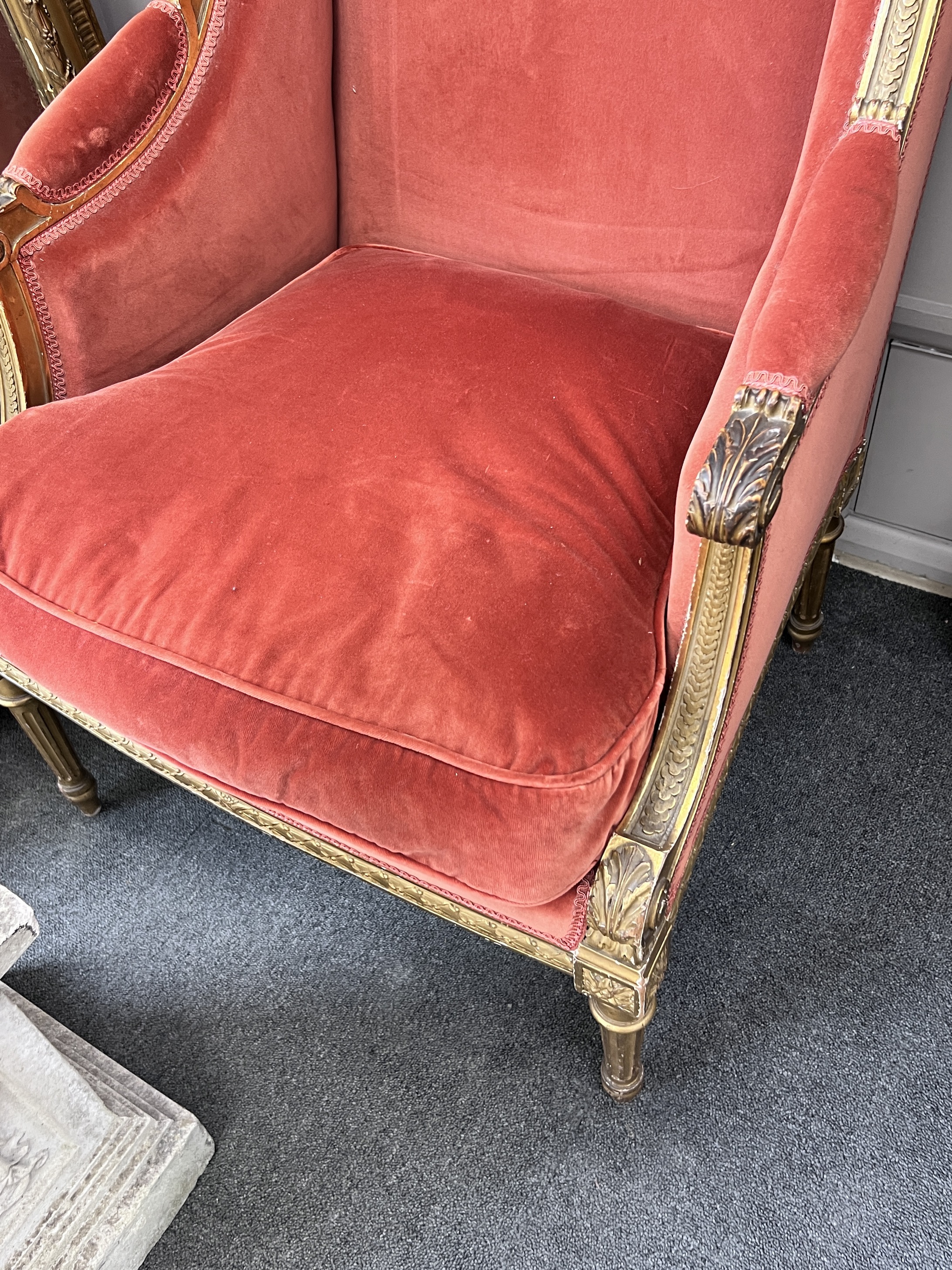 A late 19th century French Louis XVI style giltwood carved upholstered winged armchair, width 70cm, height 108cm